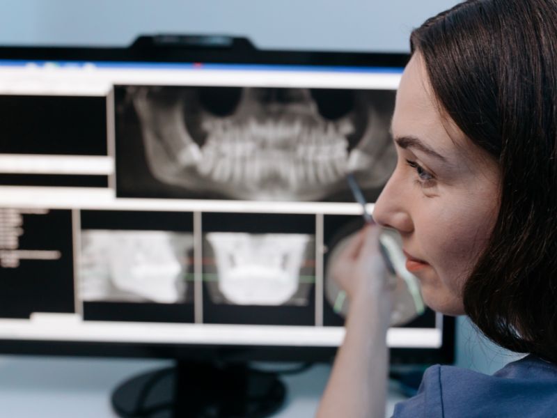 Odontología general: odontóloga mostrando radiografías de dentadura en el computador